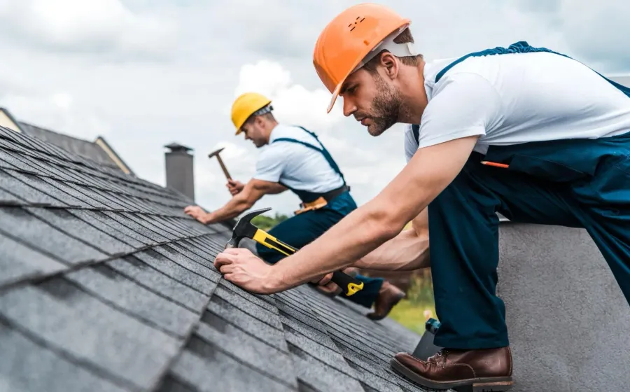 Roofers working on a pitched roof after storm damage